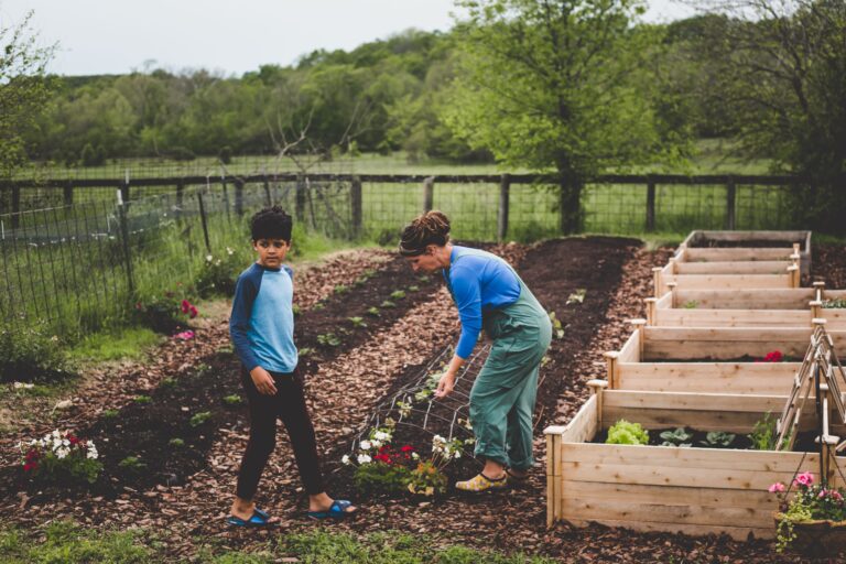 Mother and son working together in backyard garden with raised beds, amending clay soil with compost in Missouri Ozarks